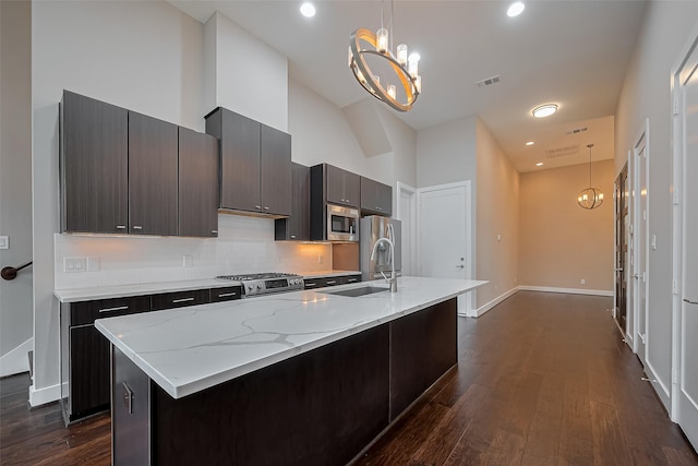 1305 Laird St, Houston, TX 77008 - kitchen featuring appliances with stainless steel finishes, backsplash, a chandelier, a center island with sink, and high vaulted ceiling