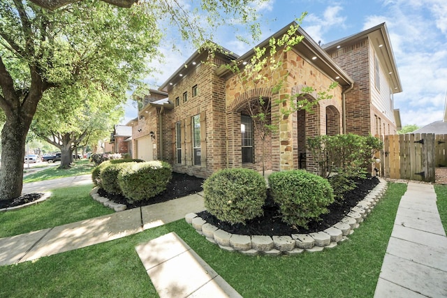 view of home's exterior featuring brick siding, fence, and a lawn