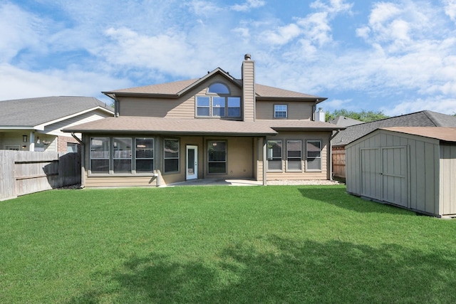 rear view of house featuring a shed, a yard, an outdoor structure, fence, and roof with shingles