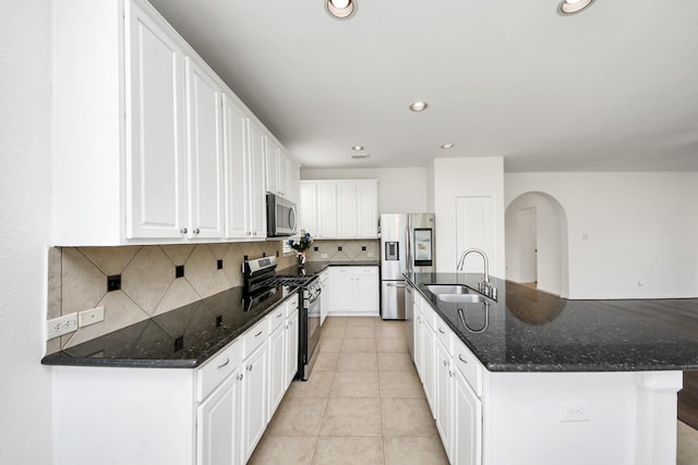 kitchen with tasteful backsplash, light tile patterned floors, white cabinetry, stainless steel appliances, and a sink