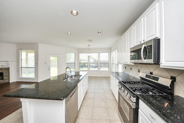 kitchen with tasteful backsplash, light tile patterned floors, white cabinets, stainless steel appliances, and a sink