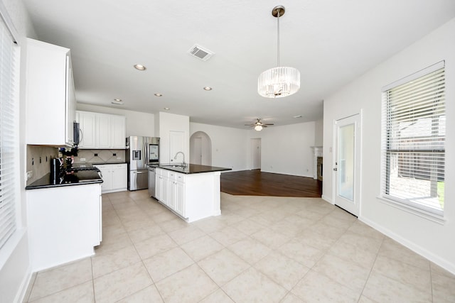 kitchen featuring tasteful backsplash, dark countertops, visible vents, appliances with stainless steel finishes, and ceiling fan with notable chandelier