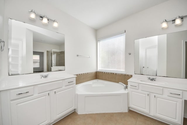 bathroom featuring two vanities, tile patterned floors, a shower stall, a bath, and a sink