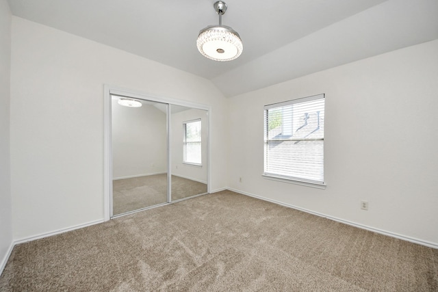 unfurnished bedroom with a closet, baseboards, vaulted ceiling, and carpet floors
