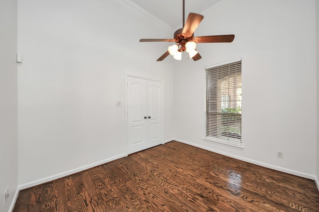 unfurnished room with dark wood-style flooring, baseboards, a ceiling fan, and crown molding