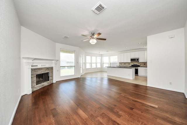 unfurnished living room with wood finished floors, ceiling fan, and visible vents