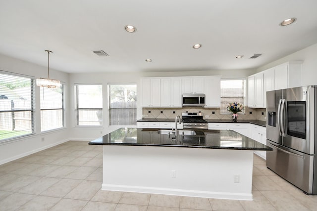 kitchen with tasteful backsplash, visible vents, white cabinets, a sink, and stainless steel appliances