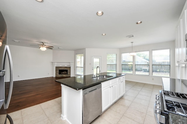 kitchen featuring a fireplace, a ceiling fan, light tile patterned flooring, stainless steel appliances, and a sink