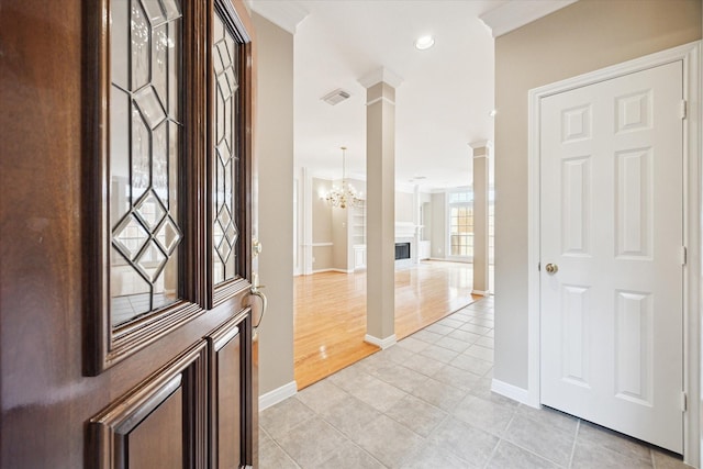 4422 Castle Court Pl, Houston, TX 77006 - foyer entrance featuring light tile patterned flooring, a fireplace, a chandelier, and ornate columns