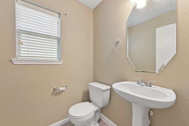 half bathroom with toilet, wood finished floors, and baseboards
