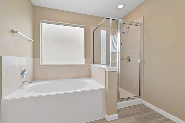 bathroom with a shower stall, a bath, wood finished floors, and baseboards