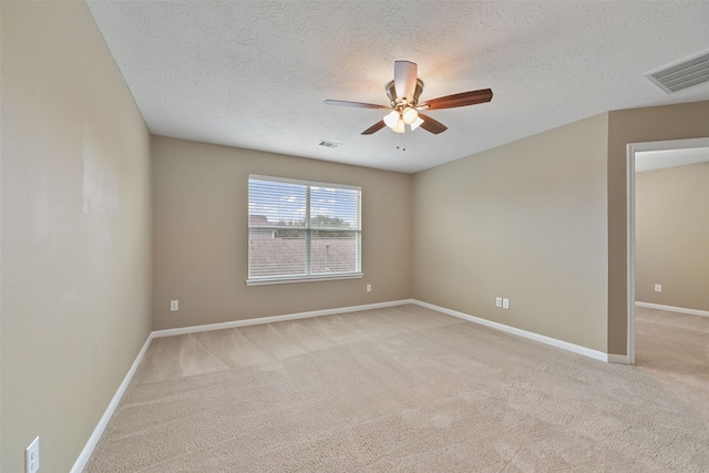 unfurnished room featuring light colored carpet, ceiling fan, visible vents, and a textured ceiling