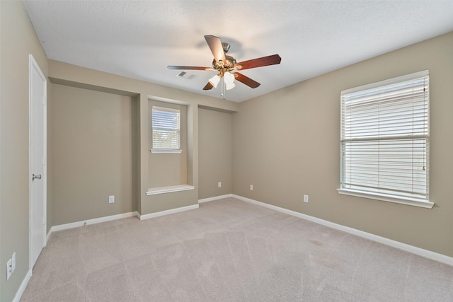 unfurnished room with visible vents, ceiling fan, light carpet, and baseboards