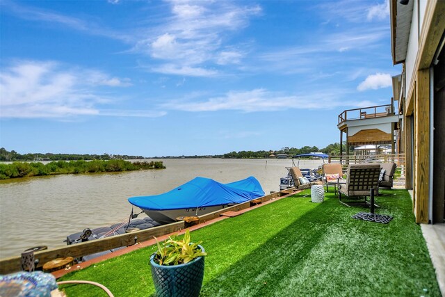 view of dock with a lawn and a water view