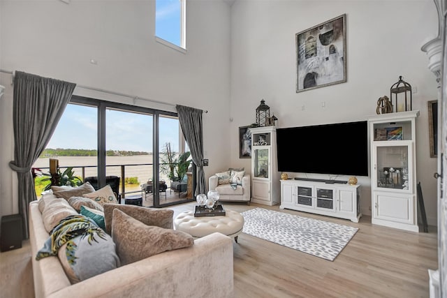 living area with a wealth of natural light, a towering ceiling, and wood finished floors