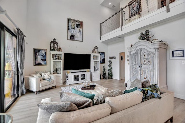 living room featuring a high ceiling, baseboards, and wood finished floors