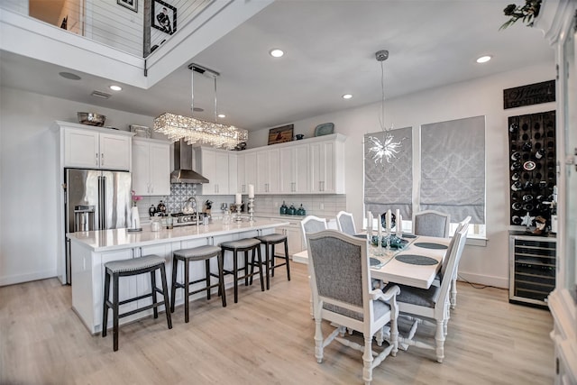 dining area featuring light wood-style flooring, wine cooler, baseboards, and recessed lighting