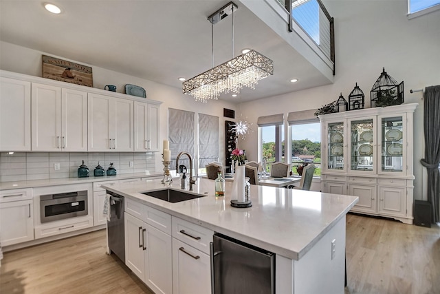 kitchen featuring a sink, light countertops, light wood-style flooring, and white cabinetry