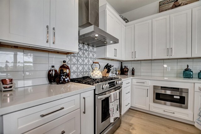 25 Cmdr Runco Ln, Taylor Lake Village, TX 77586 - kitchen featuring wall chimney range hood, stainless steel appliances, light countertops, and white cabinetry