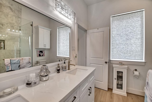 full bath with a sink, toilet, double vanity, wood finished floors, and a stall shower