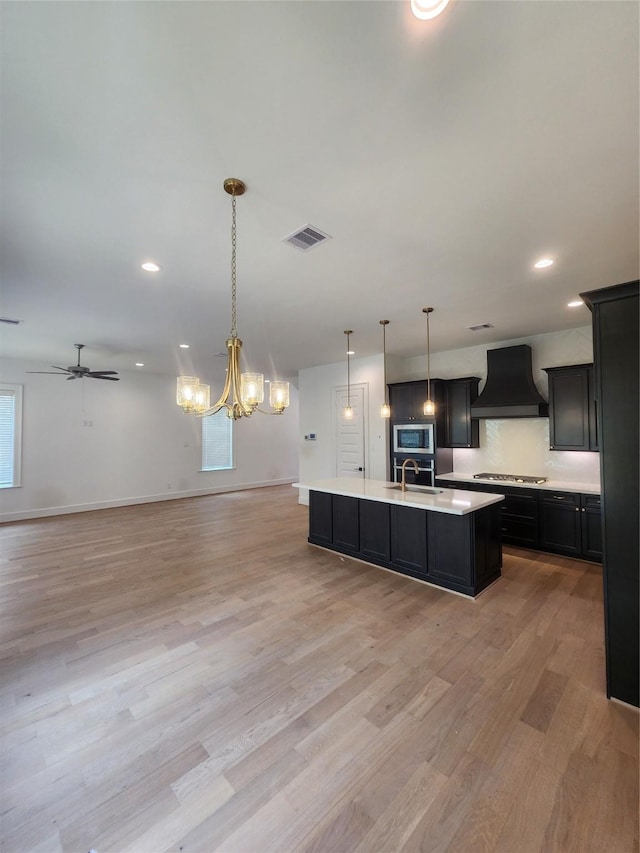 409 Forest Reserve Pl, Houston, TX 77079 - kitchen featuring custom range hood, appliances with stainless steel finishes, open floor plan, a sink, and light countertops