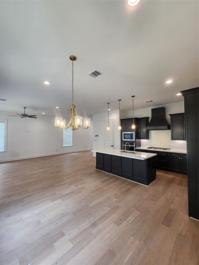 409 Forest Reserve Pl, Houston, TX 77079 - kitchen featuring custom exhaust hood, appliances with stainless steel finishes, open floor plan, a sink, and light countertops