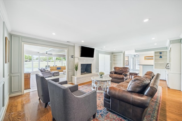 living area featuring a wealth of natural light, a fireplace, light wood-style floors, and ornamental molding