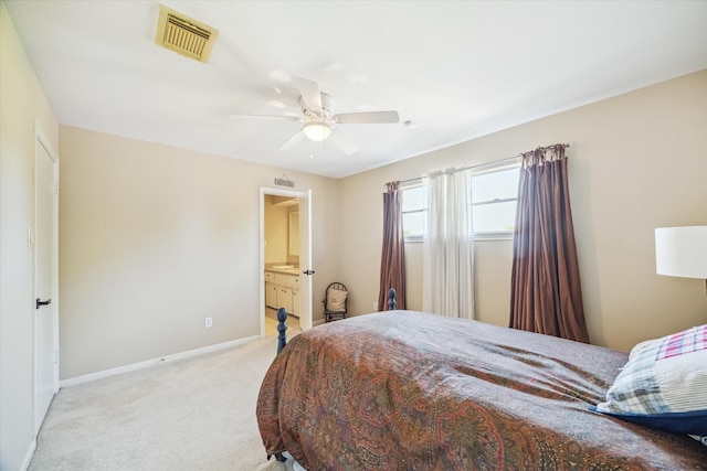 bedroom featuring visible vents, baseboards, ensuite bathroom, a ceiling fan, and light carpet