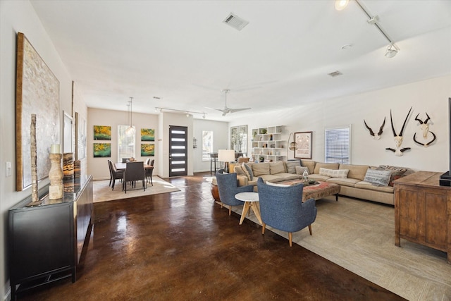 living area featuring visible vents, rail lighting, and finished concrete flooring