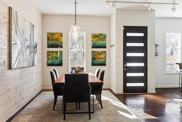 dining space featuring plenty of natural light, wooden walls, and track lighting