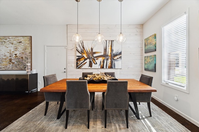 dining room with wooden walls, baseboards, and wood finished floors