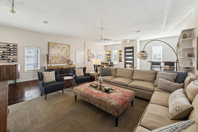 living room featuring rail lighting, baseboards, a ceiling fan, and visible vents