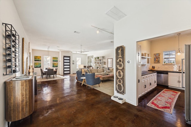interior space with finished concrete flooring, visible vents, a ceiling fan, and track lighting