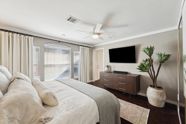 bedroom with crown molding, baseboards, a textured ceiling, and dark wood finished floors