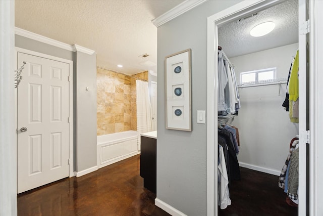 full bath with a textured ceiling, concrete floors, ornamental molding, a walk in closet, and baseboards