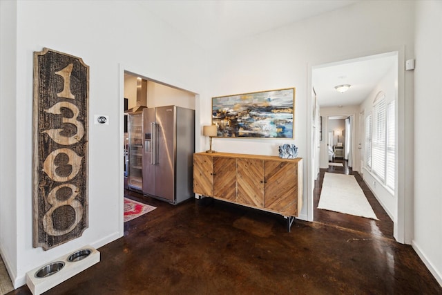 hallway featuring concrete flooring and baseboards