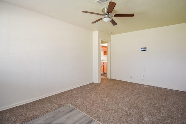 empty room with ceiling fan, light colored carpet, and baseboards