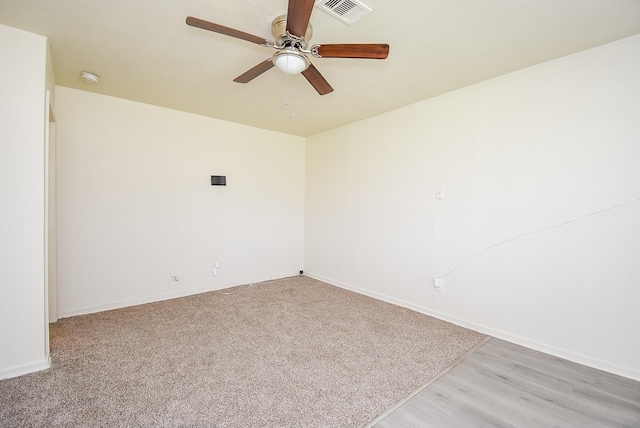 spare room with visible vents, baseboards, light colored carpet, and ceiling fan