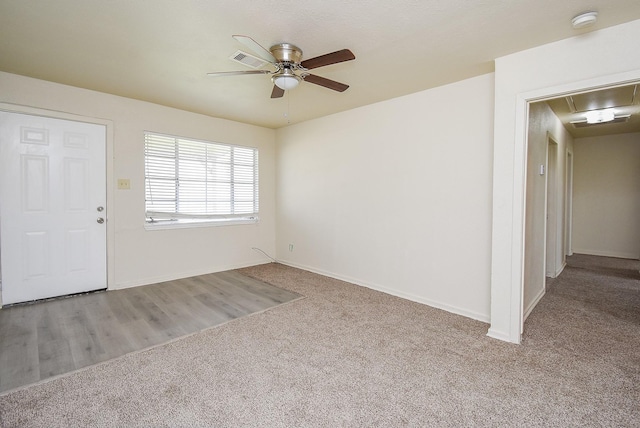 carpeted spare room with attic access, ceiling fan, baseboards, and visible vents