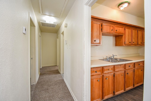 kitchen featuring brown cabinetry, visible vents, light countertops, a sink, and baseboards