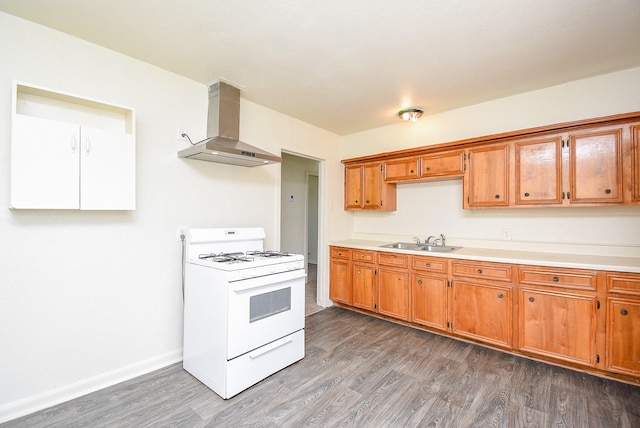 kitchen with light countertops, white range with gas cooktop, wood finished floors, and wall chimney range hood