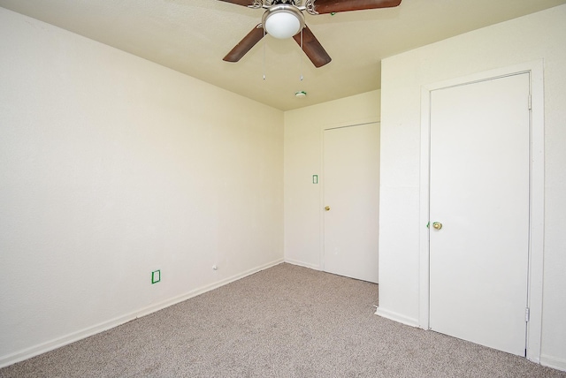 carpeted spare room featuring baseboards and a ceiling fan