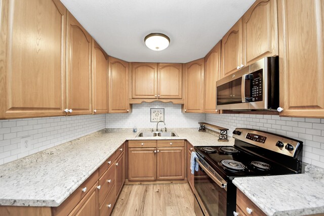 8335 Jernigan Rd, Conroe, TX 77306 - kitchen with light stone countertops, a sink, light wood finished floors, stainless steel appliances, and tasteful backsplash