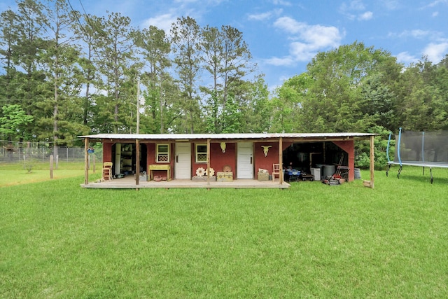 8335 Jernigan Rd, Conroe, TX 77306 - back of house with a lawn, a trampoline, fence, and metal roof