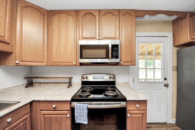 8335 Jernigan Rd, Conroe, TX 77306 - kitchen with decorative backsplash, stainless steel appliances, wood finished floors, and light stone countertops