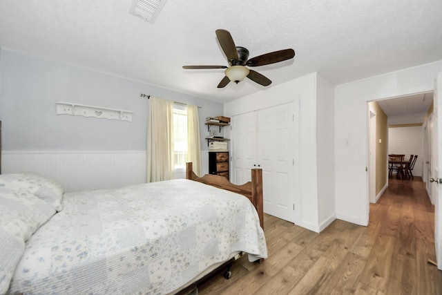 8335 Jernigan Rd, Conroe, TX 77306 - bedroom with ceiling fan, a wainscoted wall, wood finished floors, visible vents, and a closet