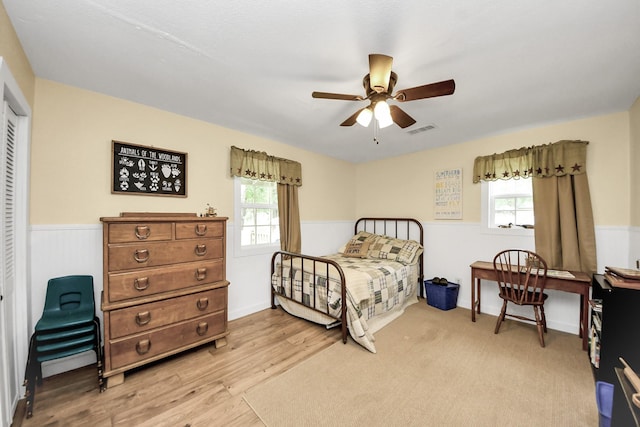 8335 Jernigan Rd, Conroe, TX 77306 - bedroom with ceiling fan, visible vents, a wainscoted wall, a closet, and light wood finished floors