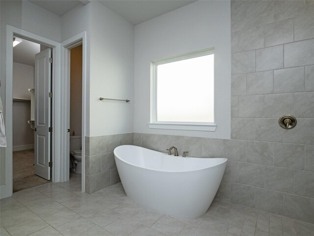19103 Timpson Dr, Cypress, TX 77433 - bathroom with tile walls, a freestanding tub, tile patterned flooring, and toilet