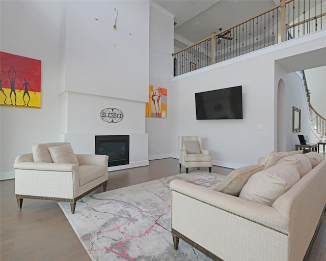 19103 Timpson Dr, Cypress, TX 77433 - living room featuring a towering ceiling, arched walkways, a glass covered fireplace, baseboards, and wood finished floors