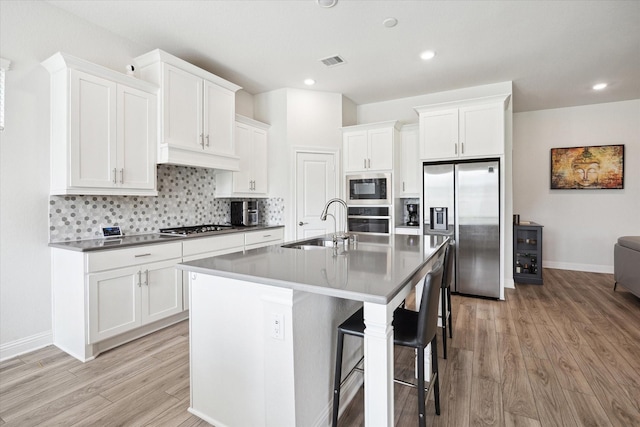 29035 Nectar Island Ln, Katy, TX 77494 - kitchen featuring stainless steel appliances, a sink, light wood finished floors, white cabinets, and recessed lighting